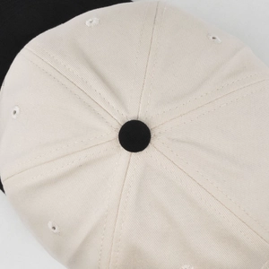 Macro shot of two-tone baseball cap top showing stitching and embroidered eyelets