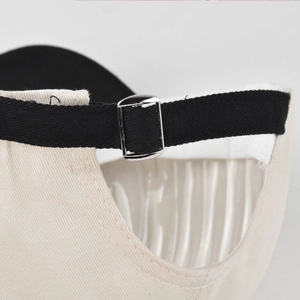 Detail of baseball cap rear showing off-white canvas and black adjustable strap with silver buckle