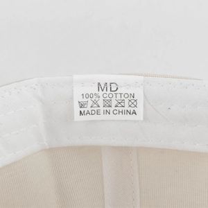 Macro detail of 100% cotton washing label and product tags on the beige baseball cap