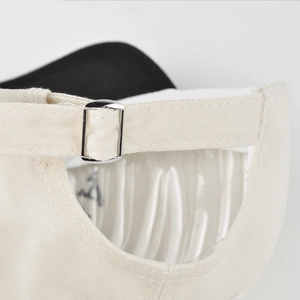 Detailed macro view of the adjustable silver metal buckle on a beige canvas baseball cap