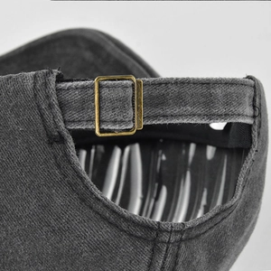 Detail der verstellbaren Metallschnalle und des gewaschenen Denim-Riemens am grauen Cap