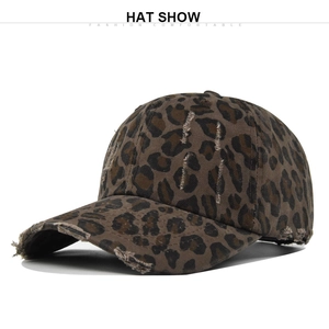 Close-up of leopard print baseball cap with distressed torn fabric and washed canvas texture