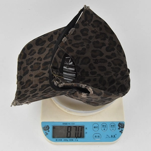 Detailed view of leopard print baseball cap weighing 87.0g on a scale