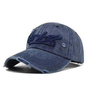 Macro detail of vintage New York embroidery on washed denim baseball cap with distressed brim