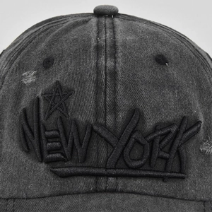 Detailed macro view of 3D embroidered NEW YORK logo on vintage grey washed cotton baseball cap