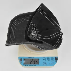 Close-up of vintage black distressed baseball cap on a scale showing 83.5g weight