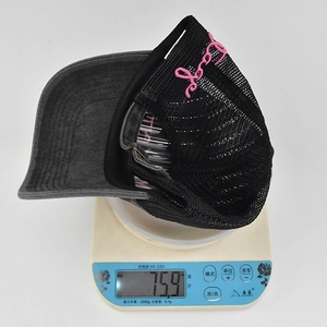 Detailed macro view showing the side pink cursive embroidery on a vintage gray denim cap