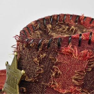 Macro shot of a reddish-brown woven cowboy hat with a sheriff star badge and leather stitching