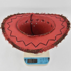 Top view of a red cowboy hat with fringe edges being weighed on a digital scale
