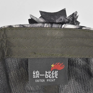 Nahaufnahme der Tarnmütze mit olivgrünem Schirm und aufgenähtem United Front Logo-Patch
