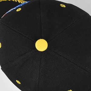 Detail of black baseball cap crown with yellow embroidered eyelets and button