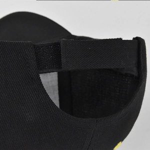 Close-up of the adjustable Velcro strap on the back of a black cotton baseball cap