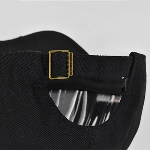 Close-up of adjustable strap and vintage metal buckle on black cotton baseball cap