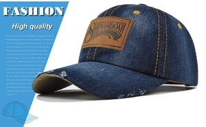 Close-up of vintage washed denim baseball cap featuring distressed holes and leather patch