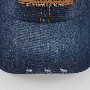 Macro detail of distressed denim brim with frayed edges and brown leather logo patch