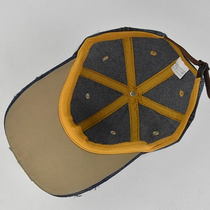 Detail view of denim cap interior with yellow seam tape and leather back strap