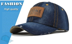 Detailed macro view of distressed denim baseball cap with brown leather Doug Stone patch