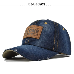 Close-up of distressed blue denim baseball cap with leather patch and yellow stitching