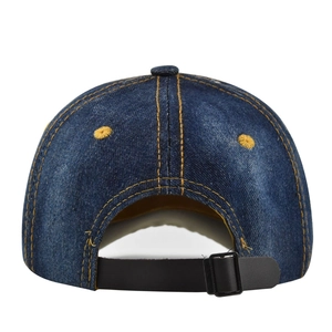 Close-up of adjustable black leather strap and yellow stitching on vintage blue denim cap