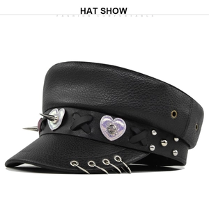 Detail of black faux leather military hat with metal rings, studs and heart patch