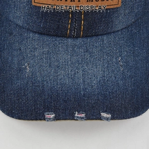 Close-up of distressed denim baseball cap edge with torn detail and leather patch