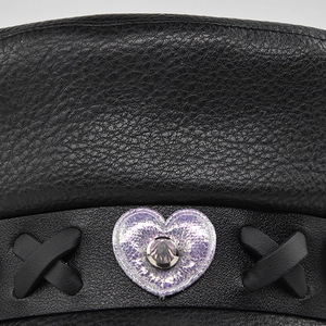 Detail of lychee pattern leather hat featuring purple sequin heart and metal rivet