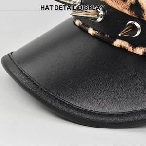 Close-up of punk style leopard print beret featuring black leather brim and silver cone studs