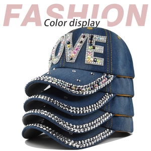 Dettaglio di cappellini in denim blu impilati con scritta LOVE in strass e visiera decorata