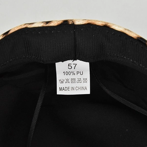 Detail view of leopard print beret interior with 100% PU material label and size 57 tag