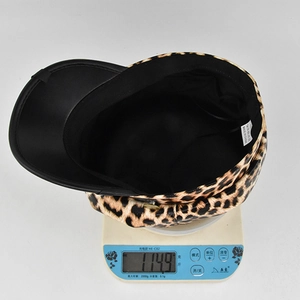 Detailed view showing the leopard print newsboy cap weighing 114.9 grams on a digital scale