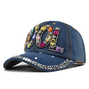 Dettaglio delle lettere COOL in strass colorati e gemme argentate su berretto in denim