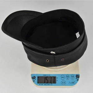 Detail shot of black PU leather flat top cap weighing 157.7g on digital scale