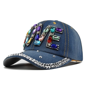 Dettaglio del cappellino in denim con lettere LOVE in strass colorati e borchie in metallo