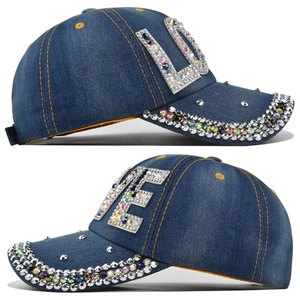 Dettaglio del motivo LOVE in strass su berretto in denim blu scuro con cuciture gialle