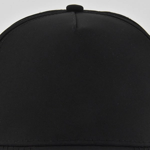 Close-up of the crown stitching and top button on a black cotton baseball cap