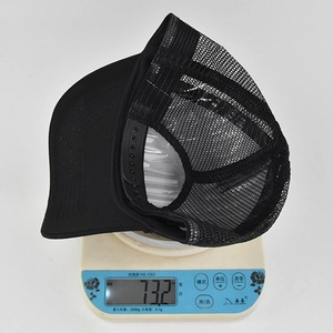 Detailansicht einer schwarzen Mesh-Basecap auf einer Waage mit einem Gewicht von 73,2g