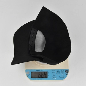 Detail view of a 66.4g lightweight black cotton baseball cap on an electronic scale