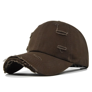 Détail de casquette de baseball marron foncé usée avec trous vintage et texture coton