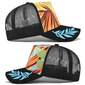 Detail of trucker hat showing blue leaf embroidery on brim and tropical floral print panel