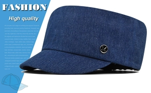Detail van een marineblauwe denim legerpet met een zilveren metalen M-logo op de zijkant