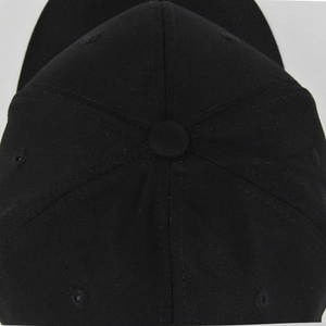 Close-up of black cotton baseball cap top showing stitching and ventilation eyelets