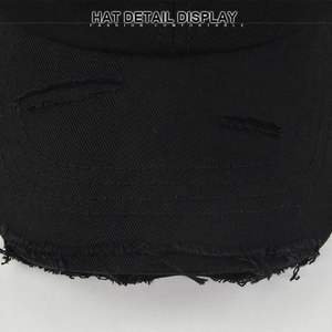 Gros plan de la visière usée d'une casquette noire avec détails déchirés et surpiqûres