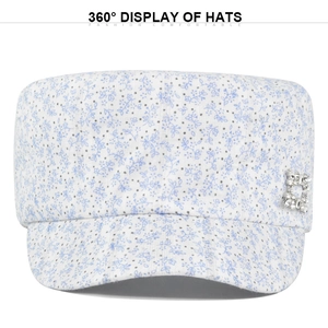 Detail view of white flat top cap with blue floral pattern and silver rhinestone buckle