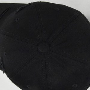 Vue détaillée du dessus montrant les effets déchirés sur une casquette en coton noir