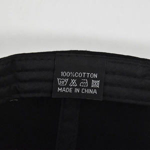 Détail de l'étiquette de lavage 100% coton sur une casquette de baseball noire usée