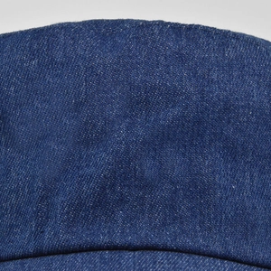 Detailopname van de donkerblauwe denim keperstof op de kroon van de platte pet