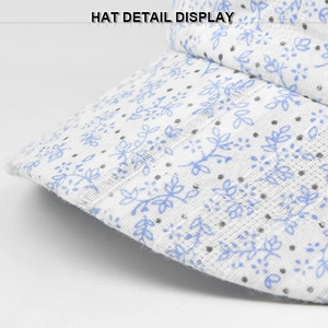 Detail view of woven floral fabric with blue leaves and grey dots on a white sun hat