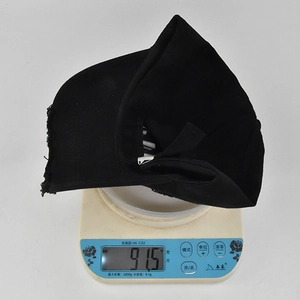 Gros plan d'une casquette de baseball noire usée sur une balance indiquant le poids