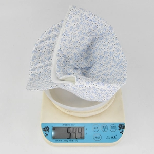 Flat top floral baby sun hat on a digital scale weighing approximately 54.4 grams