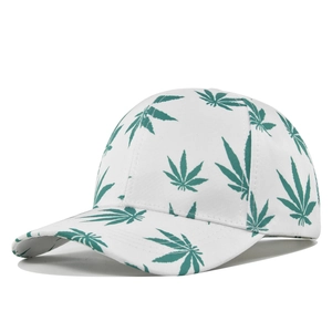 Close-up of white cotton baseball cap with green marijuana leaf prints and stitched brim